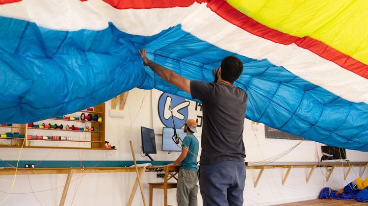 Lucas et Geoffrey de dos, en train de déployer une voile de parapente dans leur atelier